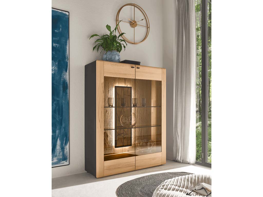 hartmann Knud - Highboard | 7111 | B: 115 cm Vitrine aus Holz mit Glasfront, dekoriert mit Pflanze oben und mit stilvollem Beleuchtungseffekt, neben großem Fenster