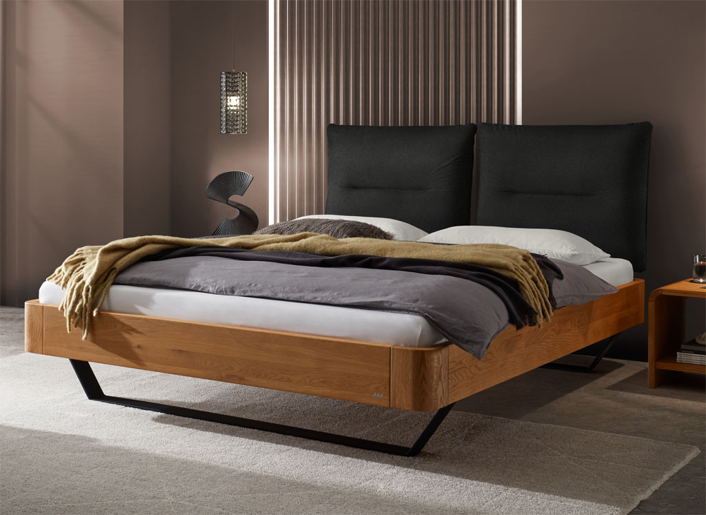 modernes Bett mit braunem Rahmen und schwarzen Metallfüßen sowie einen zweigeteilten schwarzen Kopfteil stilvoll dekoriert in einem modernen Zimmer