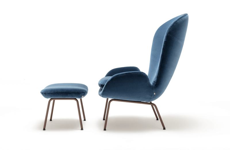 Seitenansicht eines modernen blauen Lounge-Sessels mit passendem Hocker auf Metallbeinen.