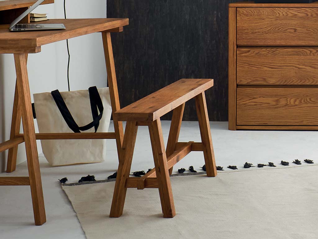 braune kleine Holzbank vor einem braunen Sekretär in einem modernen Zimmer