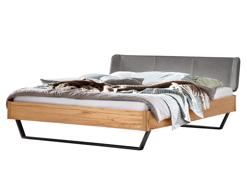 Ein Bett mit einem Gestell aus Wildbuche, einem gepolsterten Kopfteil in Anthrazit und einem schwarzen Metallgestell. Das Bett ist mit einer gemütlichen Bettdecke und Kissen in Braun- und Blautönen drapiert.