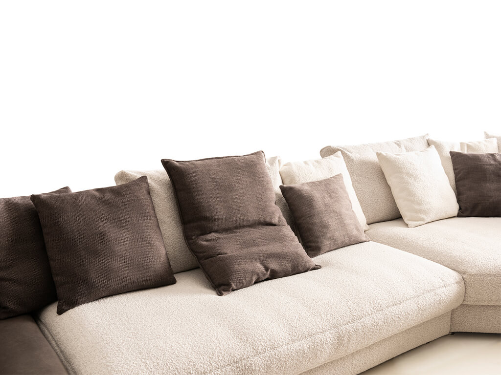 Nahaufnahme eines hellen Sofas mit verschiedenen Kissen in beige und braun Tönen