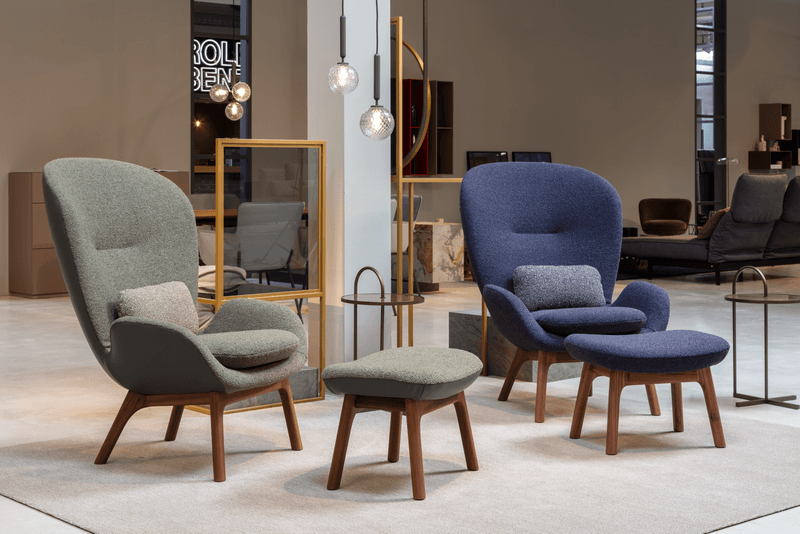 Zwei moderne Loungesessel mit Hockern in einem stilvollen Showroom, umgeben von dekorativen Elementen und Beleuchtung.