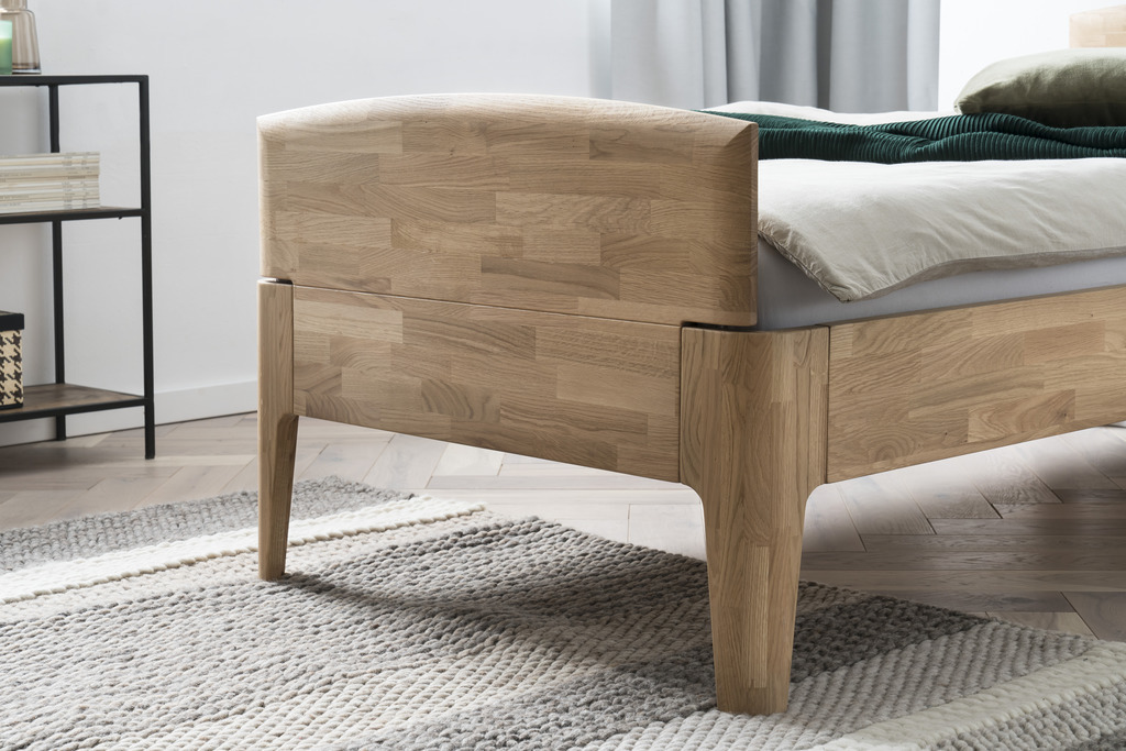 Detailaufnahme eines Holzbettes stilvoll dekoriert in einem modernen Zimmer