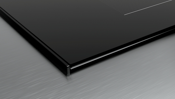 Nahaufnahme eines schwarzen Glaskeramik-Kochfelds auf einem Edelstahluntergrund