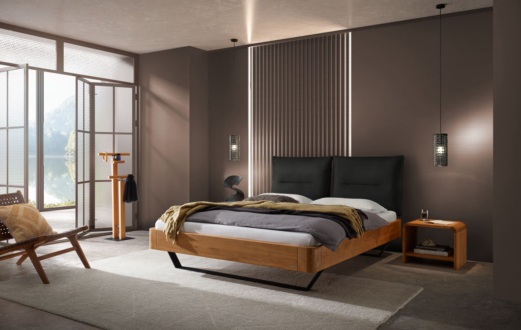 modernes Bett mit braunem Rahmen und schwarzen Metallfüßen sowie einen zweigeteilten schwarzen Kopfteil, passendem Nachtschrank stilvoll dekoriert in einem modernen Zimmer