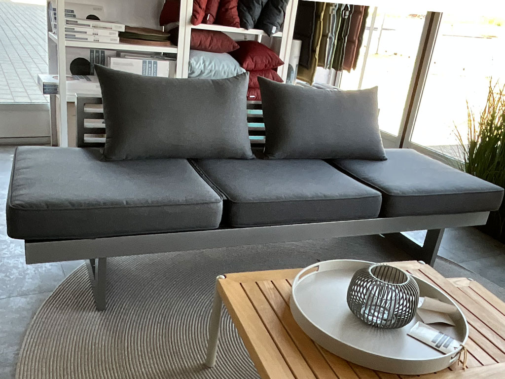 Dunkelgraues Polstersofa mit drei Sitzflächen, zwei großen Rückenkissen und schwarzem Metallgestell.
