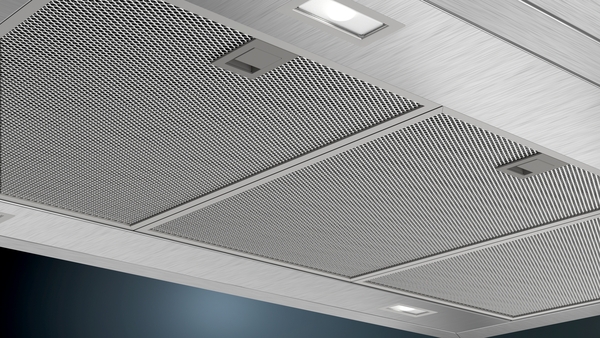 Nahaufnahme einer Edelstahl-Dunstabzugshaube mit eingebauten LED-Lichtern und Metallfiltereinsätzen