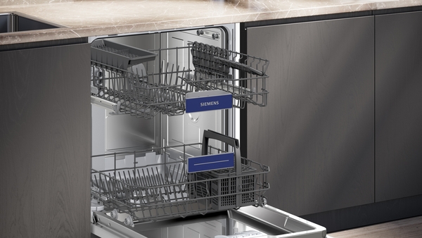 Nahaufnahme des Innenraums des Siemens Geschirrspülers. Die beiden VarioFlex Pro Körbe sind ausgezogen, auf denen blaue "SIEMENS"-Logoschilder befestigt sind.