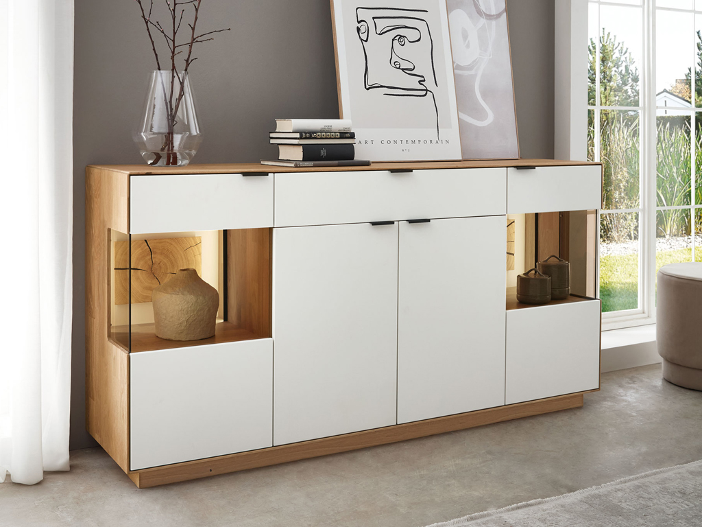 Wöstmann WM 2410 - Sideboard | Type 2842 | Lack und Wildeiche massiv | Hirnholzakzent Modernes Sideboard aus Holz und Weiß mit Vasen und Büchern dekoriert in einem hellen Raum