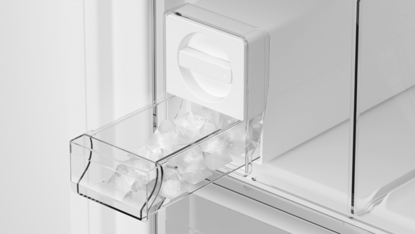 Nahaufnahme eines Eiswürfelbereiters in einem Kühlschrank, der frische Eiswürfel liefert.