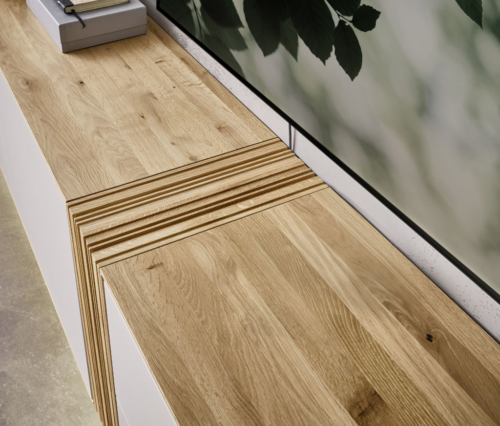 Detailaufnahme eines braun-weißen Lowboards mit markanter Holzakzentverbindung in der Mitte