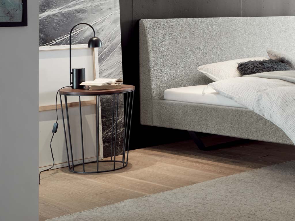 brauner runder tisch auf grauem gestell in form eines korbes in einem dunklen zimmer stilvoll dekoriert lina von hasena