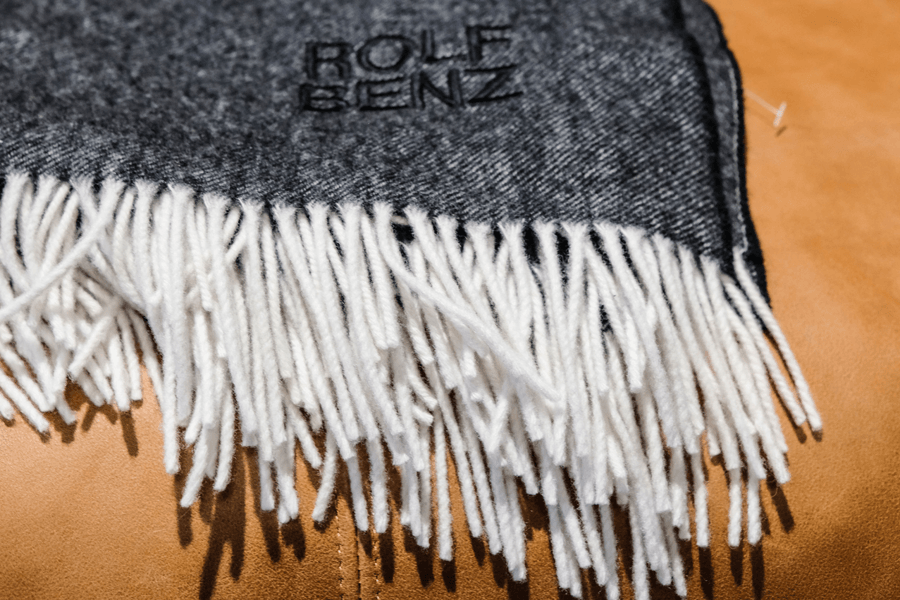 Decke oder Schal in dunkelgrau und weißen Fransen am Ende. Aufschrift Rolf Benz