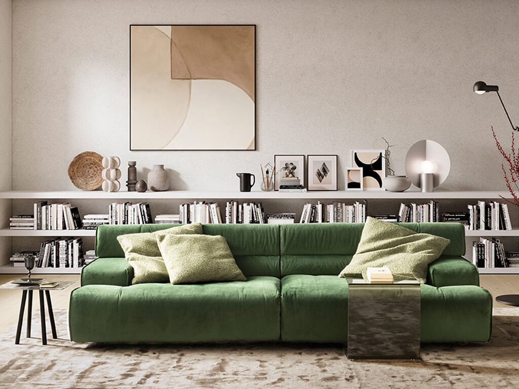 designwerk Colosseo - Polstergarnitur | B: 280 cm Ein modernes Wohnzimmer mit einem stilvollen grünen Sofa, dekoriert mit Kissen, vor einem großen Bücherregal und zeitgenössischer Kunst an der Wand.