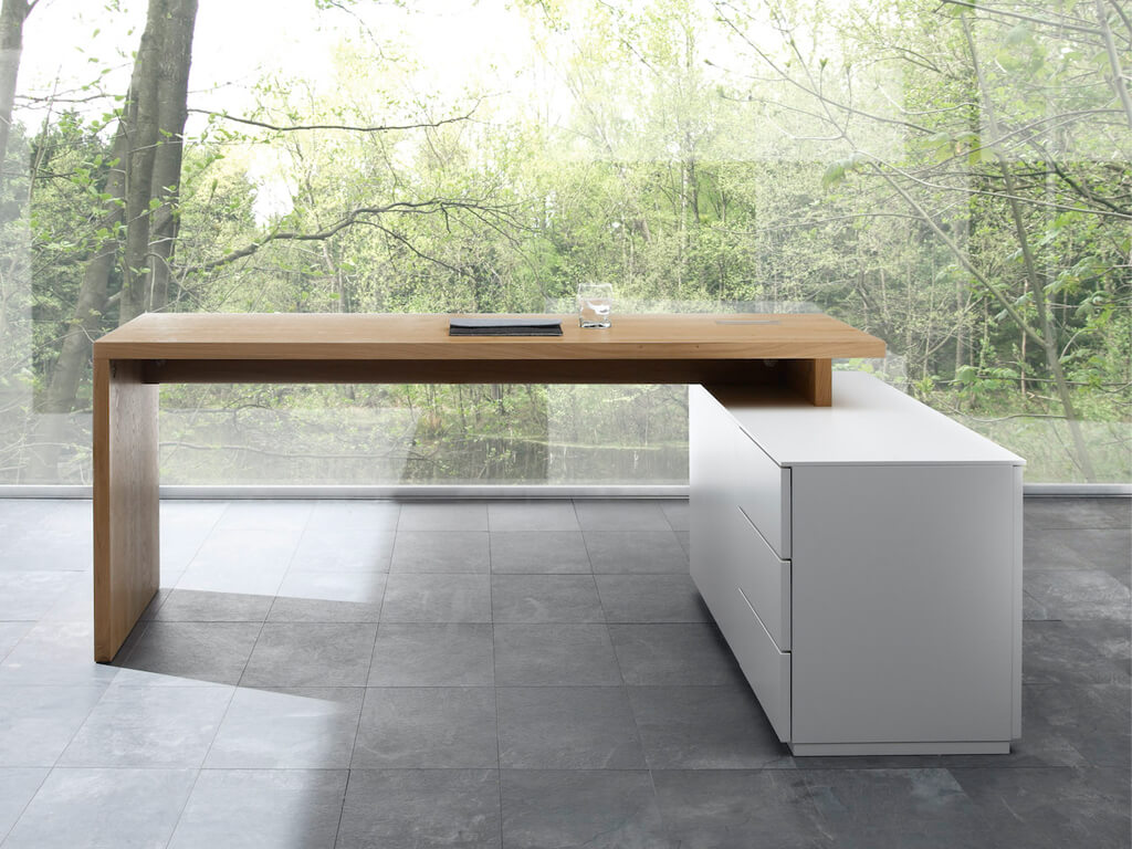 Sudbrock Cubo - Aufsatzschreibtisch mit Sideboard | B: 180 cm | Ethno Eiche furniert, Lack verkehrsweiß Moderner Schreibtisch aus Holz mit seitlichem Schubladenelement vor einer großen Glasfront mit Blick in einen Wald