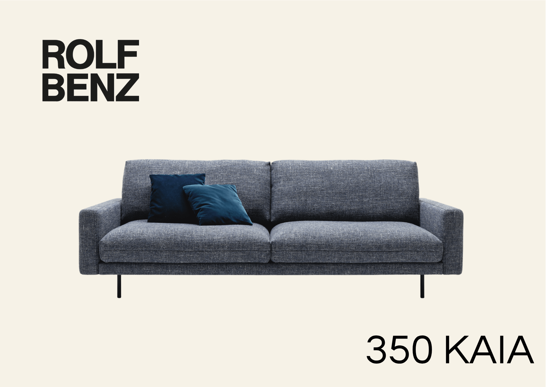 hellgraue Polsterbank mit blauen Kissen. Aufschrift Bild: Rolf Benz 350 Kaia.