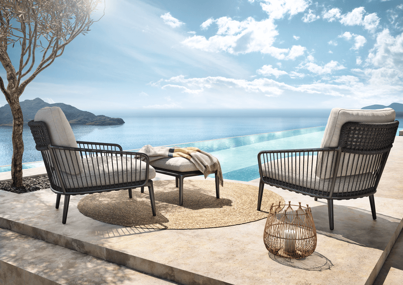 Zwei stilvolle Gartenstühle mit Kissen neben einem Infinity-Pool mit Blick auf das Meer.