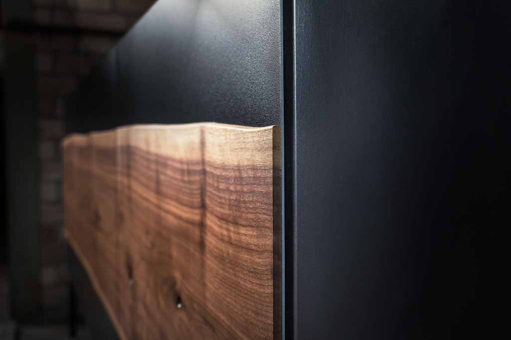 Nahaufnahme einer modernen Holzwand mit elegantem, natürlichem Holzfinish und dunklem Hintergrund, die ein stilvolles Ambiente betont