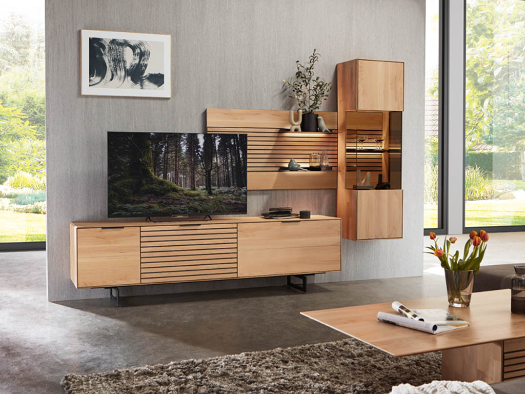 Wöstmann WM 2320 - Wohnwand  | Type 0001/0101 Stilvolles Wohnzimmer mit moderner Holz-Wohnwand, Flachbildfernseher, dekorativen Regalen und einem großen Fenster mit Gartenblick