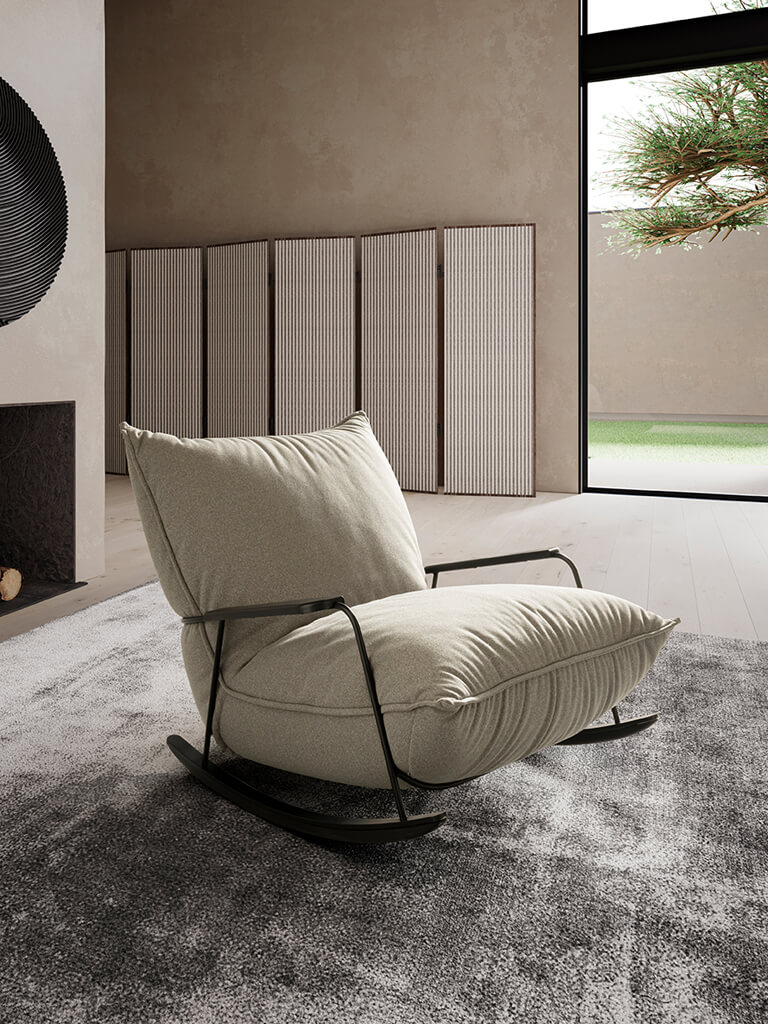 designwerk Fluffy - Sessel (Schaukelstuhl) | konfigurierbar Ein stilvoller Schaukelstuhl mit schwarzem Metallrahmen und beigem Polster auf einem grauen Teppich in einem modernen Wohnzimmer mit großen Fenstern.