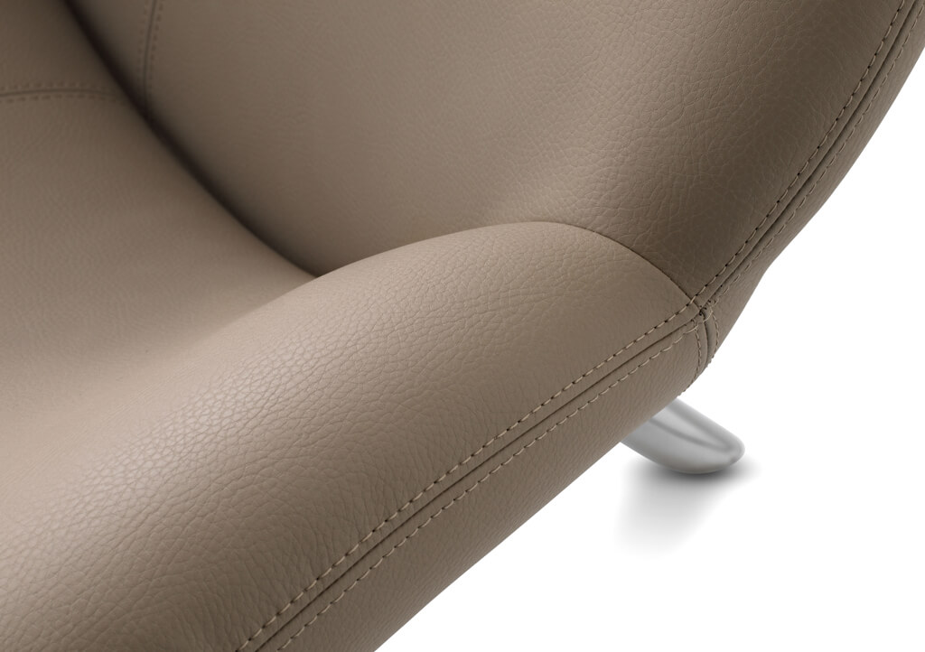 Nahaufnahme der Armlehne eines eleganten braunen Ledersessels mit feiner Struktur und silbernem Fuß