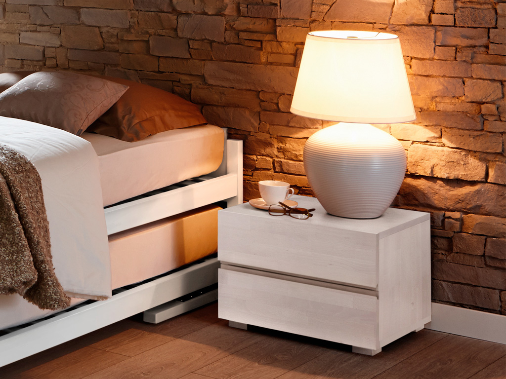weiß lackierter nachtschrank mit zwei schubladen und einer großen tischlampe mit großem schirm an einem doppelbett in einem gemütlich eingerichten zimmer dupla von hasena
