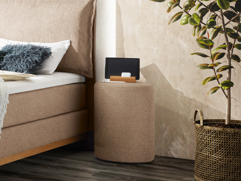beiger runder hocker vor stilvoll dekoriert an einem bett in einem modernen zimmer Dean von Hasena