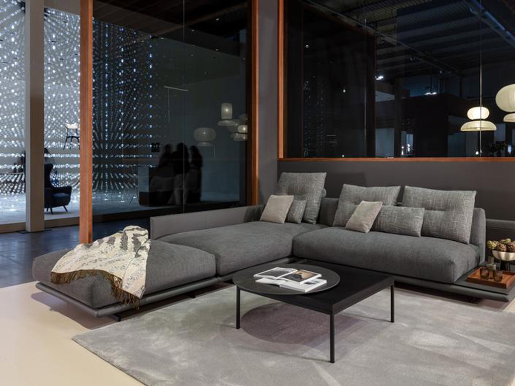 graues Sofagarnitur mit Kissen und Decke dekoriert, platziert an einem schwarzen Couchtisch in einem stilvoll eingerichtetem Raum