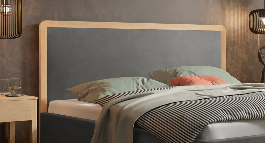 Nahaufnahme des dunkelgrauen Polsterkopfteils mit massiver Holzeinfassung aus heller, geölter Eiche in einem Schlafzimmer (KI-generiert)