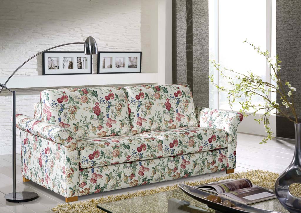 Restyl Cleo - Schlafsofa (Faltbett) | gemustert | 150 x 200 cm Ein Sofa mit floralem Muster steht in einem modern eingerichteten Wohnzimmer neben einer Stehlampe und einem Tisch.