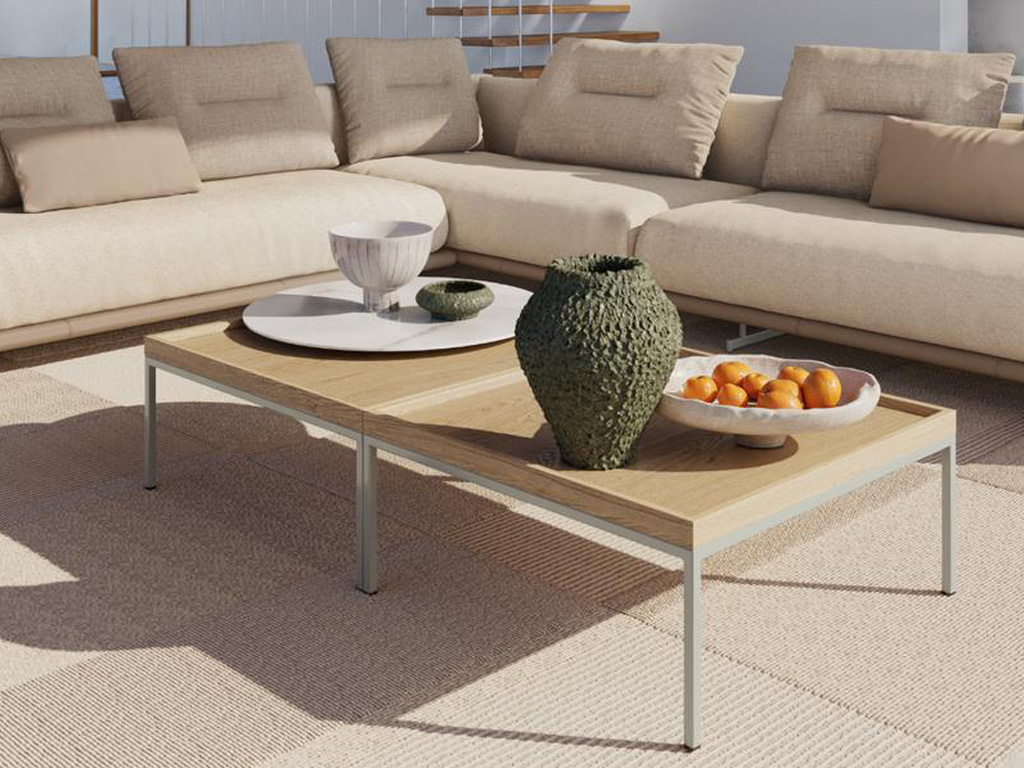 rechteckiger Designercouchtisch mit heller Tischplatte und rundem weißen Tablett stilvoll dekoriert an einer beigen Couch auf beigem Teppich in einem mediterranen Ambiente