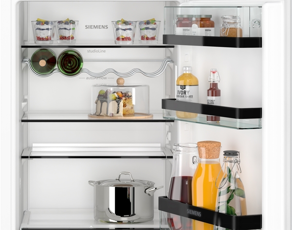 Offener Siemens Kühlschrank gefüllt mit Lebensmitteln, Glasflaschen und einem Kochtopf, elegant arrangiert