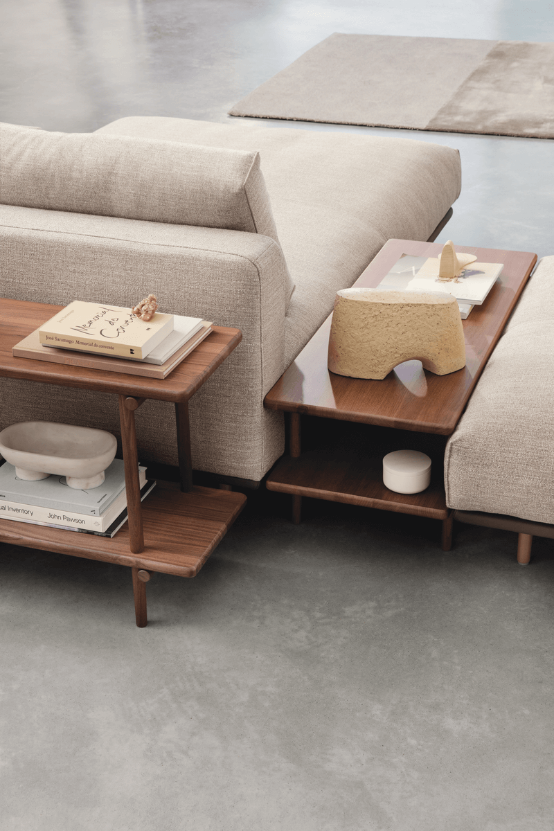 Bequemes, beiges Sofa mit hölzernen Beistelltischen, dekoriert mit Büchern und Kunstobjekten in einem modernen Wohnzimmer