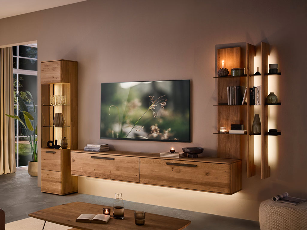 moderne Wohnwand aus Eiche mit einem Hängelowboard, beleuchtetem Regal und beleuchteter Vitrine stilvoll dekoriert in einem modernem Zimmer