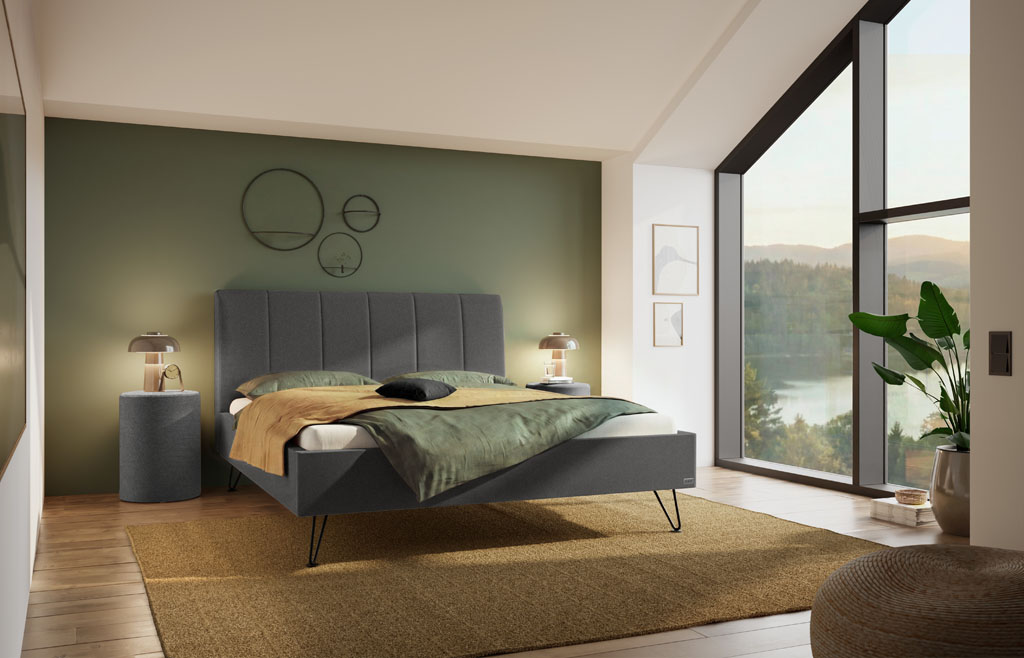 Dunkelgraues Polsterbett mit vertikal gestepptem Kopfteil und schwarzen Metallfüßen in einem modern eingerichteten Schlafzimmer mit großem Fenster (KI-generiert)