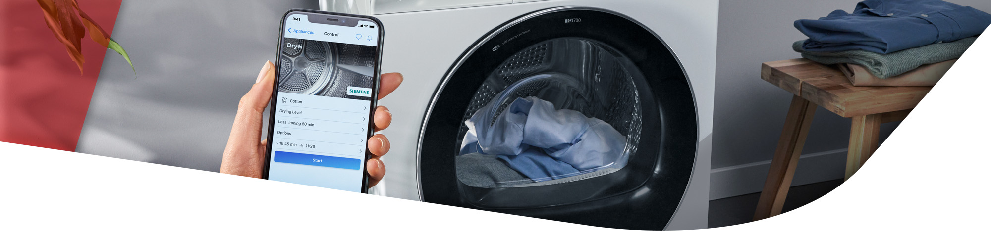 Hand mit Smartphone vor einer Waschmaschine