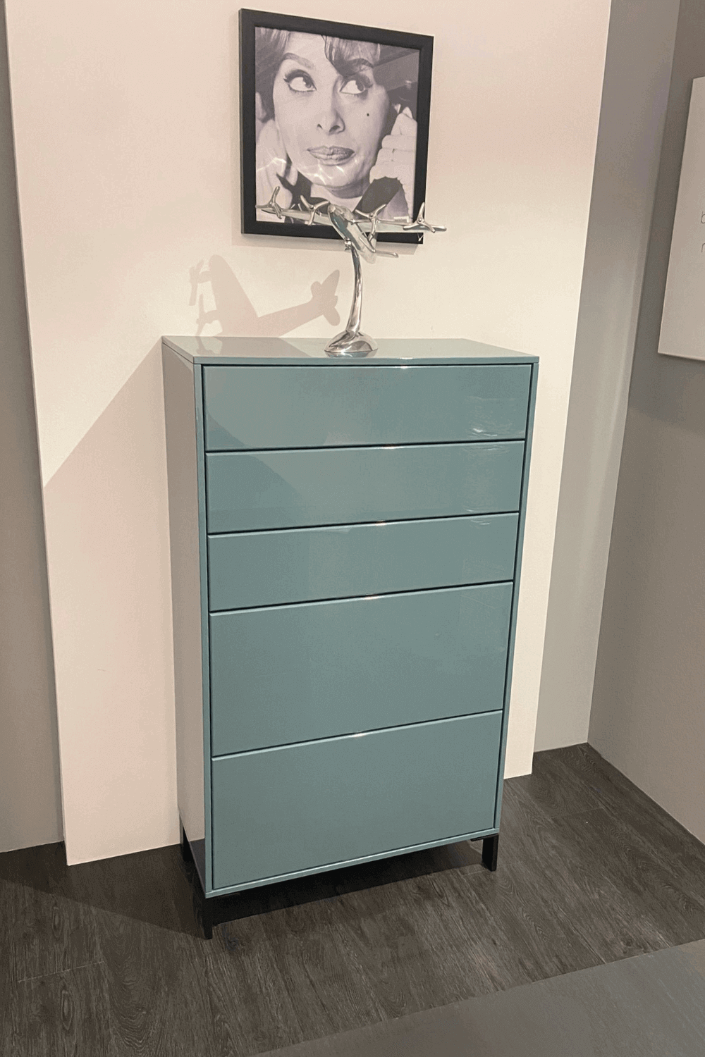 Moderner blauer Schrank mit mehreren Schubladen, dekoriert mit einem Flugzeugmodell und einer Vintage-Fotografie an der Wand