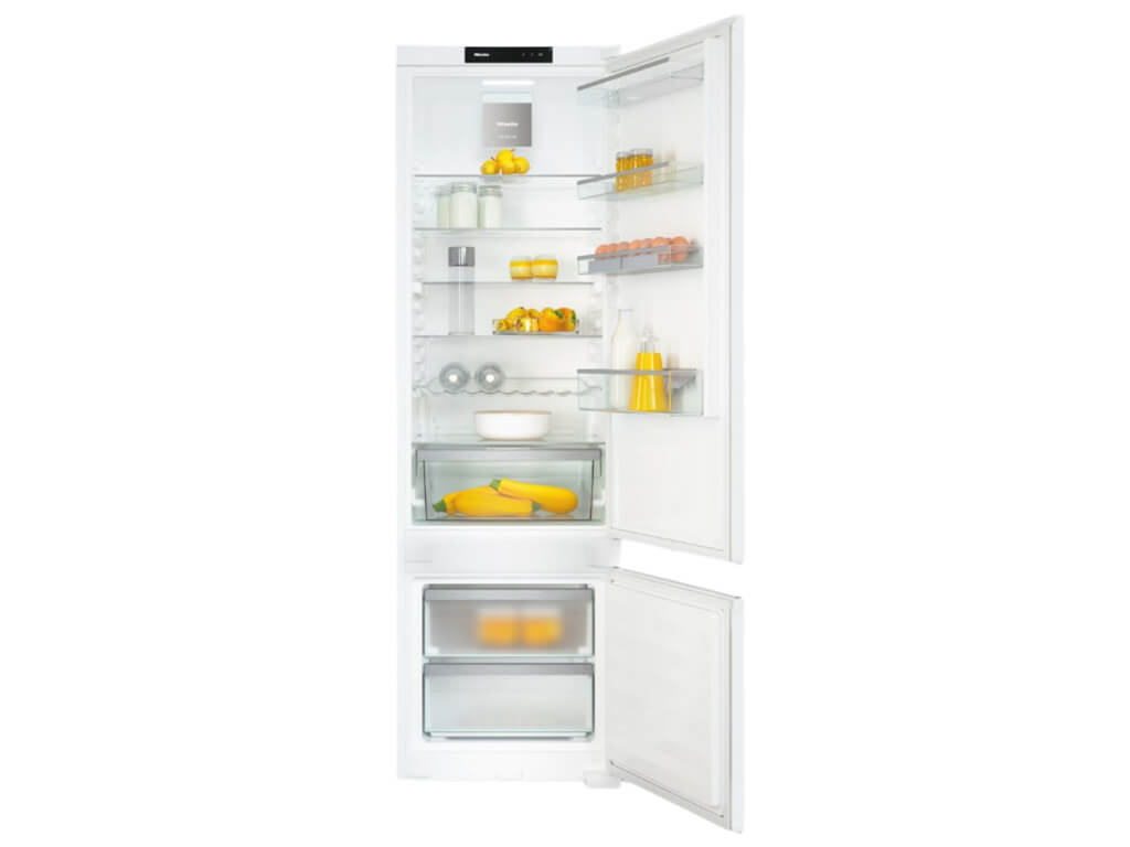 Eine Gesamtansicht des geöffneten, weißen Miele Kühlschranks. Der Kühlschrank hat mehrere Glasablagen, ein Eierfach und zwei große Schubladen am unteren Ende.