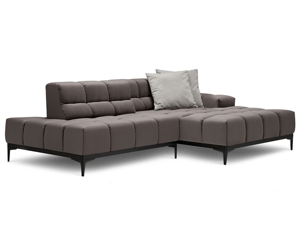 Ein L-förmiges, modulares Ecksofa in Dunkelgrau mit gesteppten Sitz- und Rückenkissen und schlanken schwarzen Metallfüßen. Ein helles, graues Zierkissen liegt auf der Rückenlehne. Der Hintergrund ist weiß.