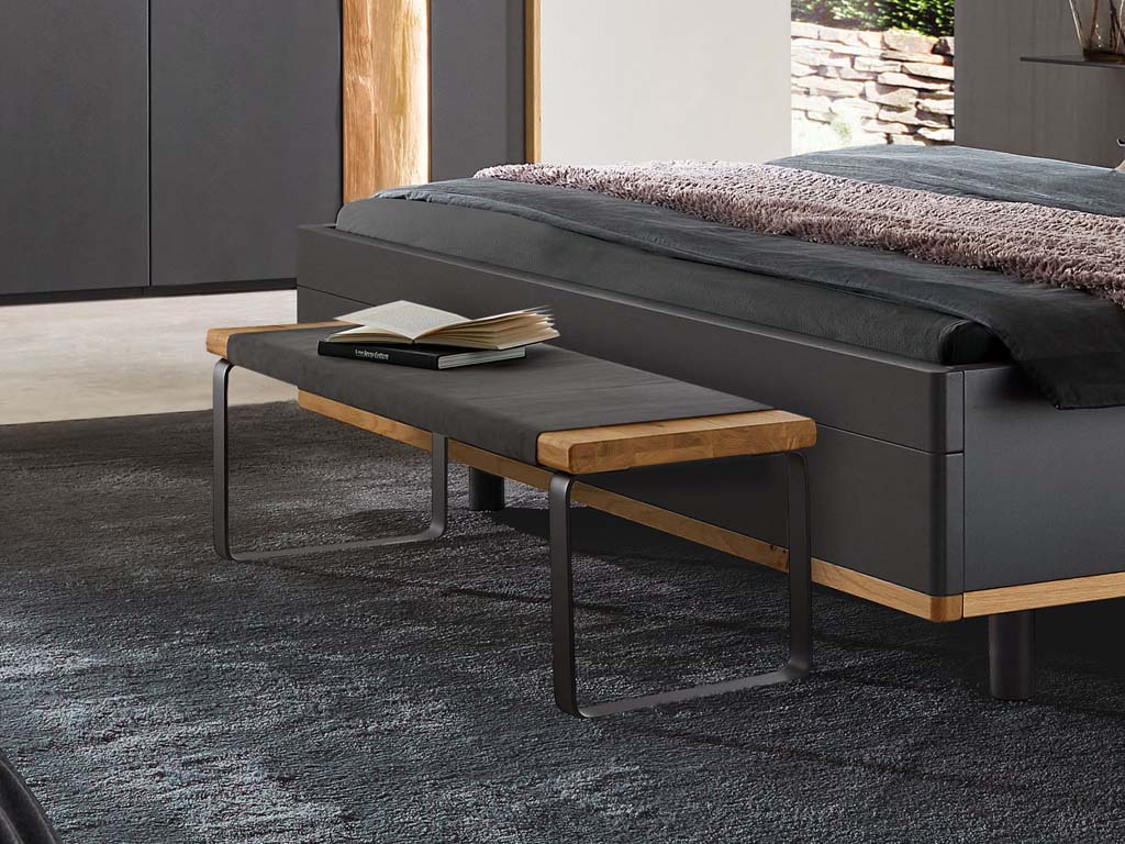 Schlafzimmerbank mit Holz- und Metallelementen vor einem Bett in einem stilvollen Schlafzimmer
