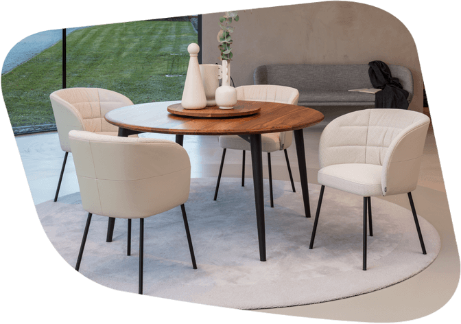 Ein stilvoller Essbereich mit rundem Holztisch und vier cremefarbenen Stühlen, auf hellem Teppich in moderner Umgebung