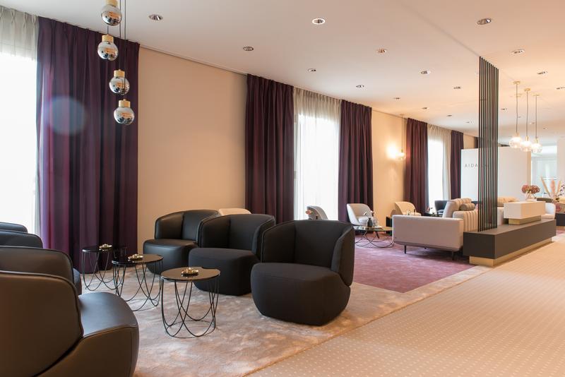 Moderner Lounge-Bereich mit schwarzen Sesseln und lila Vorhängen, stilvoll eingerichtet.