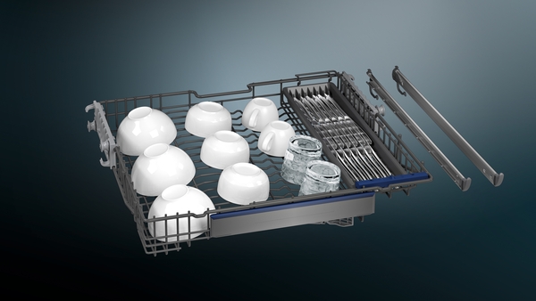 Ein geöffneter Geschirrkorb einer Spülmaschine, gefüllt mit weißen Schüsseln, Gläsern und Besteck.