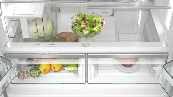 Innenansicht eines modernen Kühlschranks mit frischem Obst, Gemüse und Salat in einer Schale