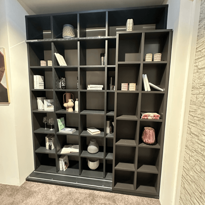 RMW. DEVISO | Regalwand Großes, dunkelgraues Bücherregal gefüllt mit Büchern, Kerzen und dekorativen Figuren in einem modernen Interieur