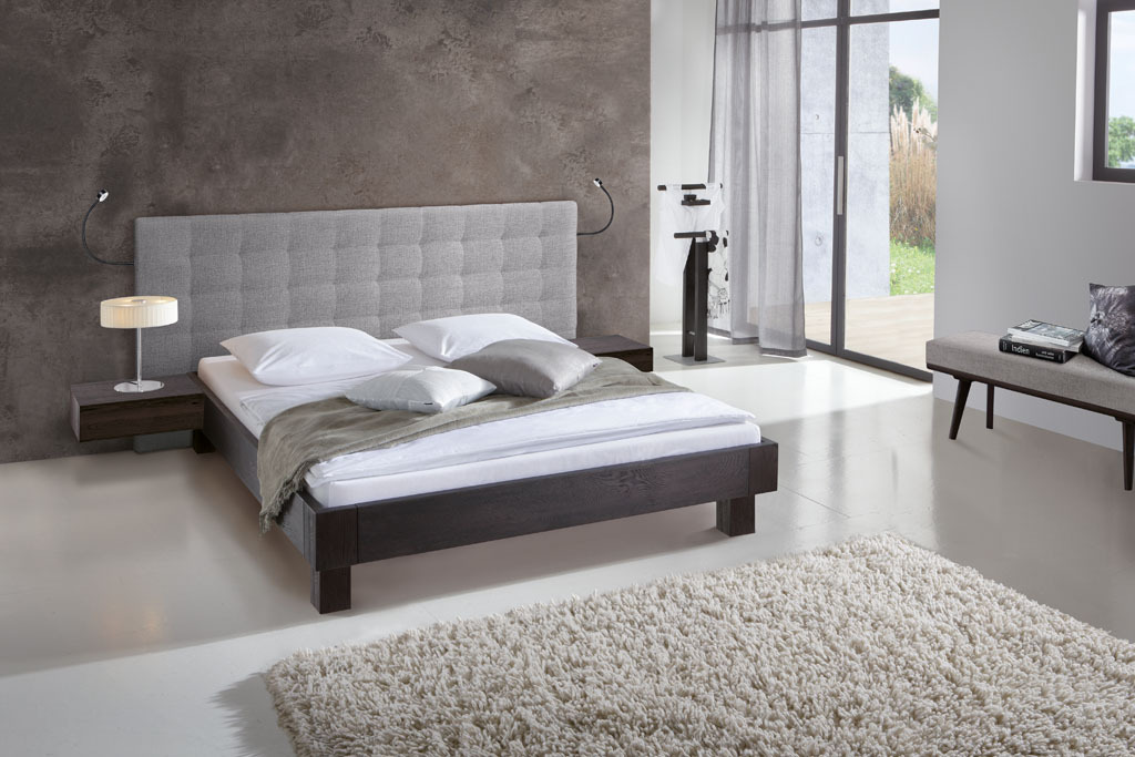 modernes Bett in schwarz mit grauem Polster als Wandpaneel stilvoll dekoriert in einem modernen Zimmer