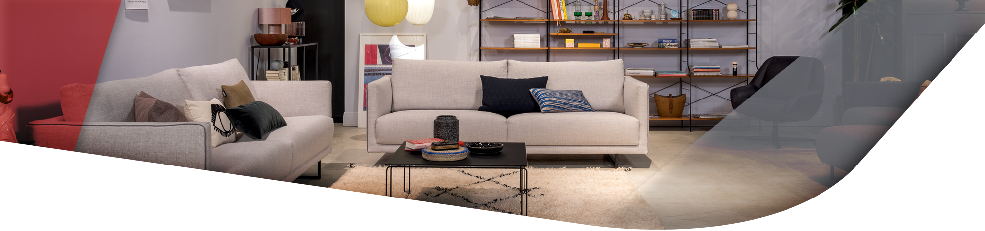 Zwei helle Sofas in beige im Wohnzimmer stehend vor einem großen Holzregal. Die Sofas sind mit dezenten Kissen dekoriert. 