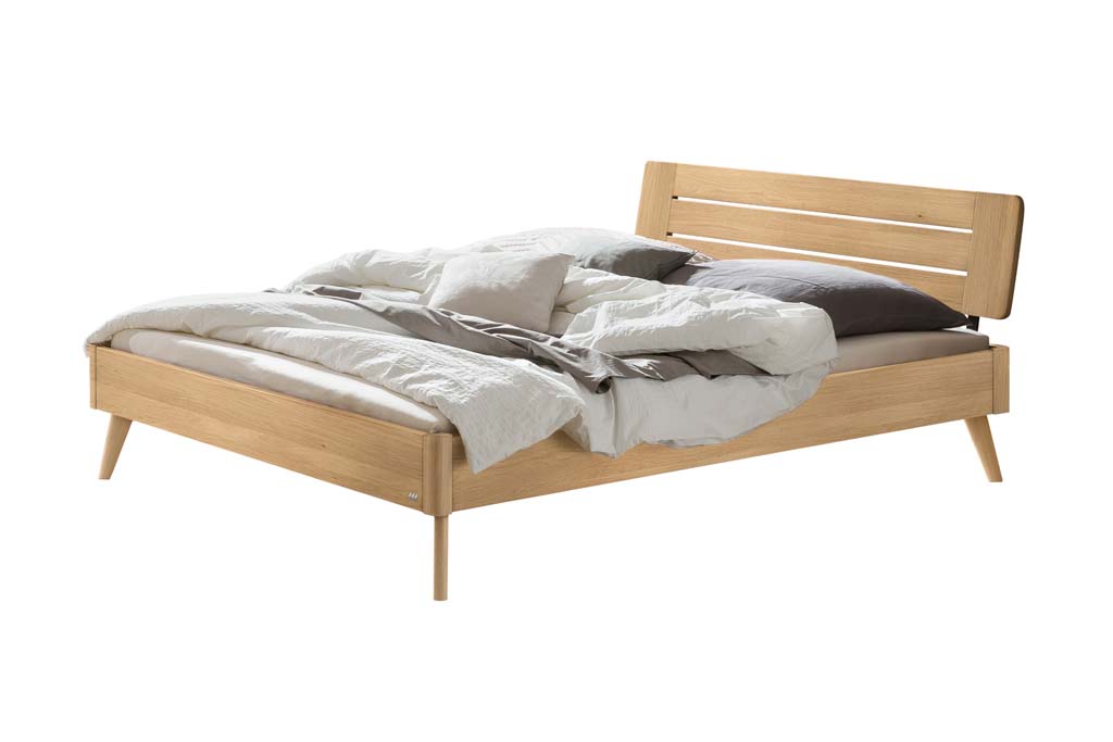 Holzbett mit Bettzeug vor weißem Hintergrund