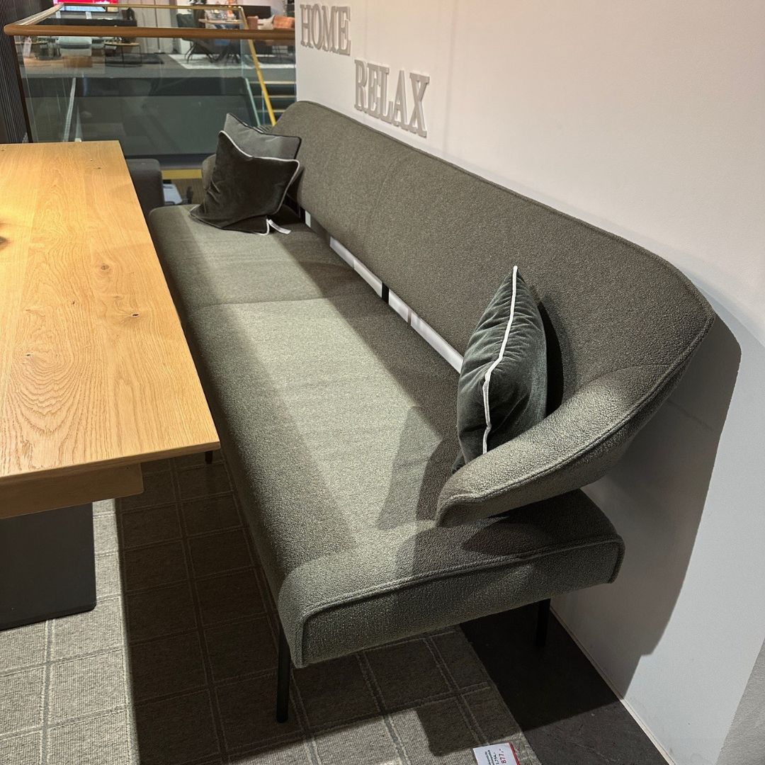 Graue Eckbank mit Kissen neben einem Holzesstisch, ideal für gemütliche Esszimmer.